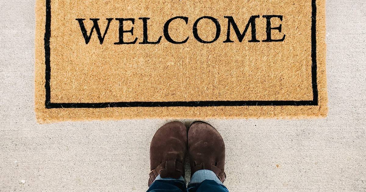 Welcome mat with lower body of person standing in front of it