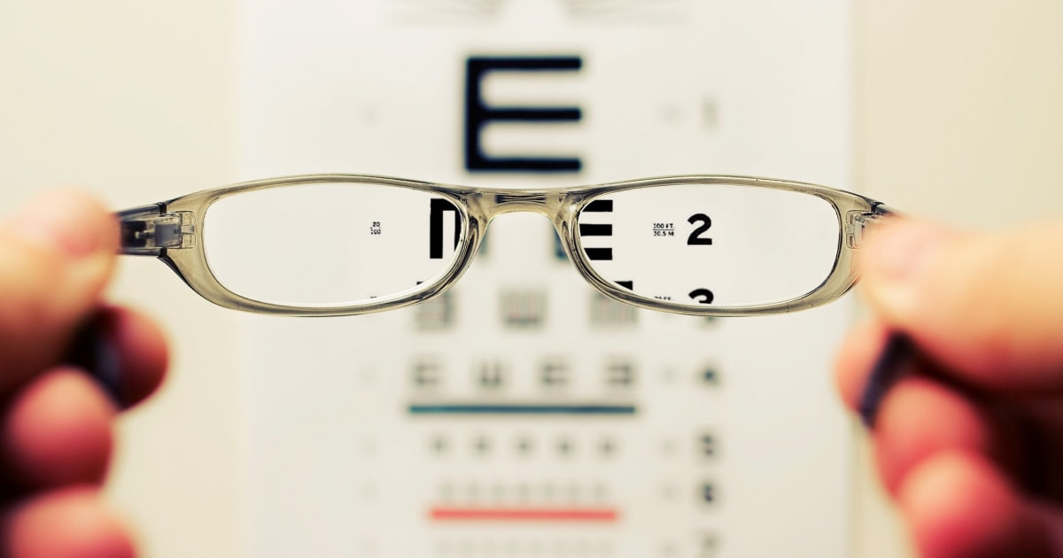 Holding glasses with eye chart in background