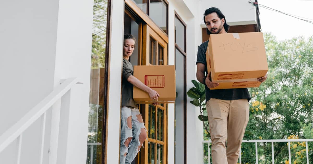 couple carrying boxes while moving out of home