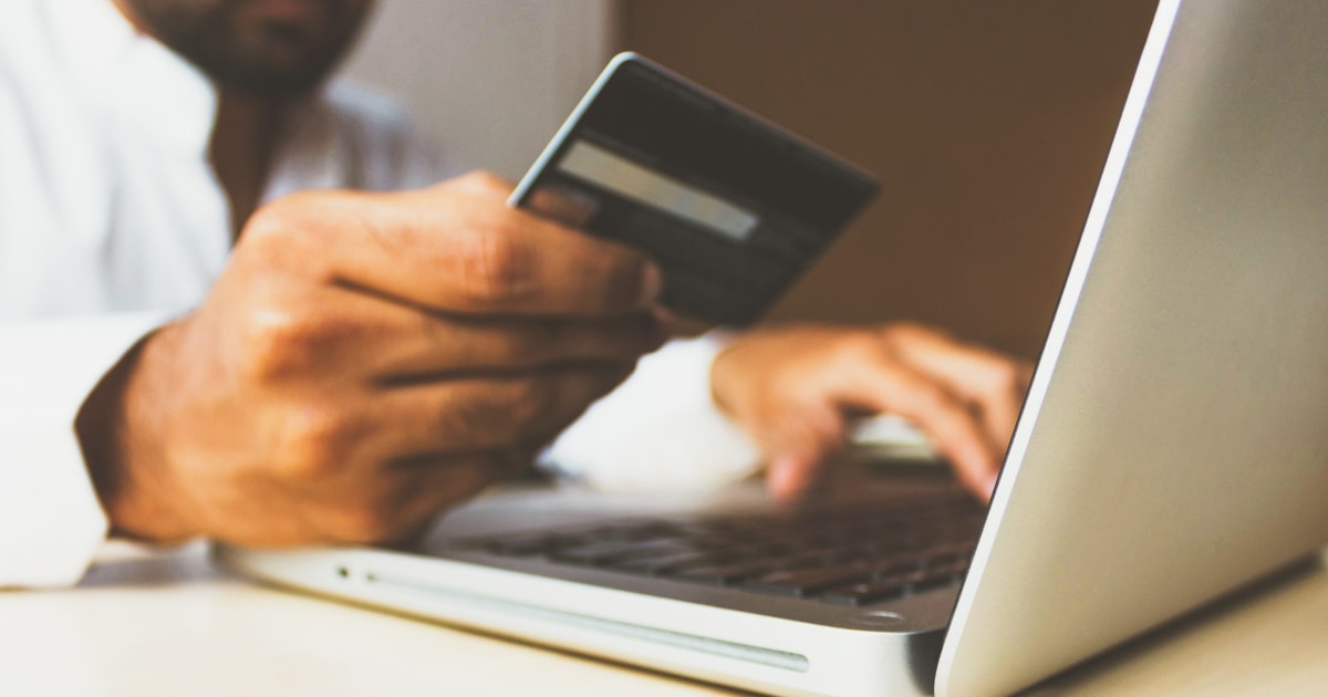 Man looking at laptop with credit card in hand