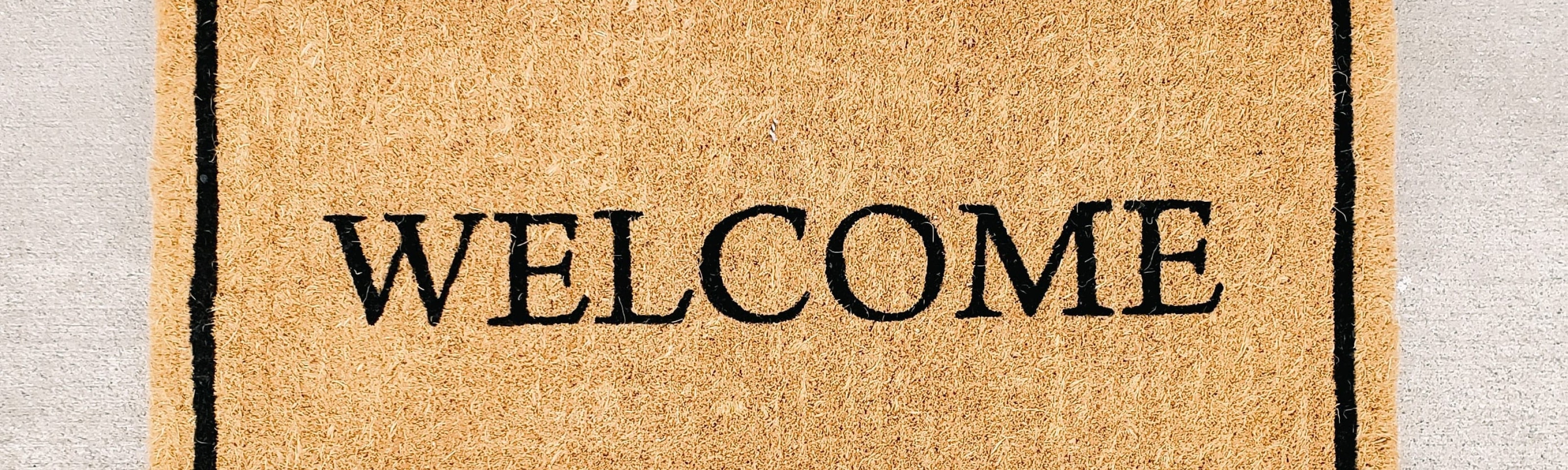 Welcome mat with lower body of person standing in front of it