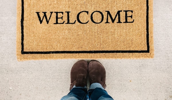 Welcome mat with lower body of person standing in front of it
